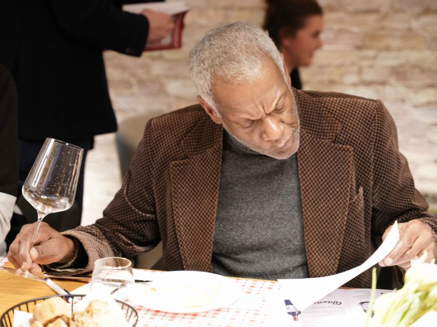 Mann hält ein Weinglas in seiner Hand und liest eine Weinbeschreibung